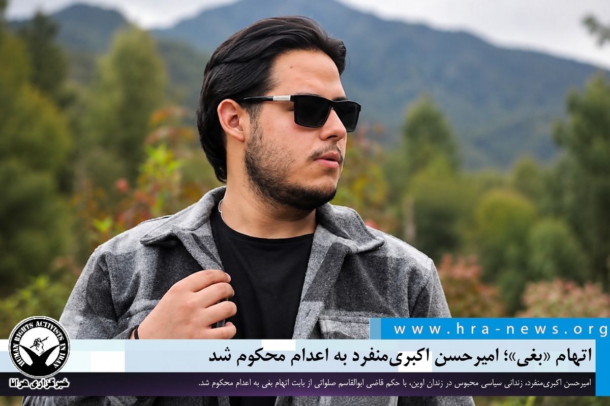 Amirhassan Akbari Monfared wearing sunglasses and a grey overshirt outdoors, in a documentary photo published by HRANA